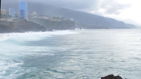 Eine-Große-Welle-Des-Atlantiks-Bricht-An-Einem-Sonnigen-Tag-Während-Eines-Sturms-In-Puerto-De-La-Cruz-Auf-Den-Kanaren-An-Einer-Felsigen-Küste,-Weitwinkelaufnahme