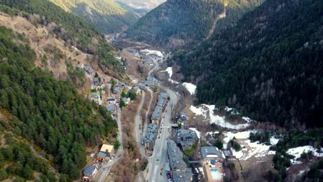 Aerial-of-small-town-seated-in-between-valley-with-snow-mountains-and-trees