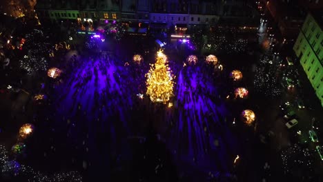 Ambiente-Festivo-En-La-Plaza-Del-Ayuntamiento-De-Kaunas-Con-Majestuoso-árbol-De-Navidad-Durante-La-Nevada,-Vista-Aérea