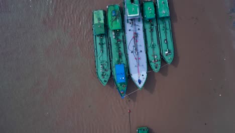 Aerial-Top-down-shot-of-working-boats-anchored-near-the-shore-on-a-clear-sunny-day