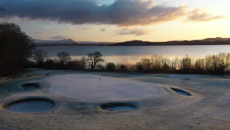 Aerial-Drone-Approach-Angle-of-Beautiful-Golf-Course-Green-at-Sunrise-in-Winter,-Golf-Course-on-Loch-Lomond
