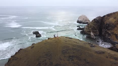 Overtake-Shot-Of-Tourists-Hiking-Over-High-Rise-Cliff,-Astonishing-Sea-View,-Peru
