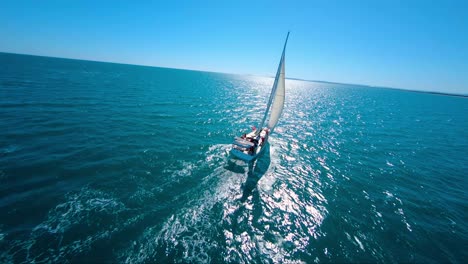 Acrobatic-cinematic-shot-of-a-sailboat-racing-through-the-tropical-ocean