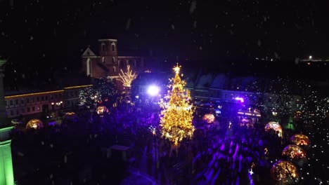 Bright-vibrant-colors-of-Kaunas-Christmas-tree-during-snowfall,-aerial-view