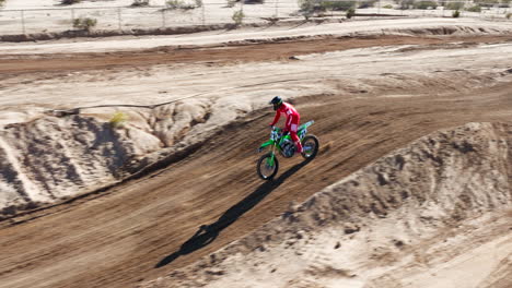 Motorcyclist-racing-on-an-off-road-dirt-track-over-jumps---slow-motion-aerial