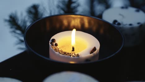 Burning-Christmas-candle-with-pine-tree-needles-in-background,-close-up-view