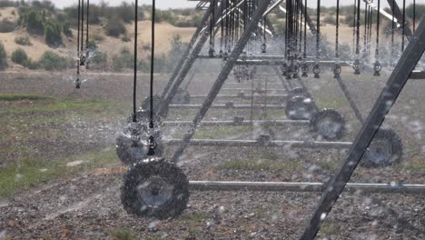 Close-up-wheel-of-pivot-at-work-in-potato-field,-watering-crop-for-growth