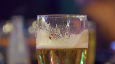 Ein-Glas-Bier-Mit-Unscharfen-Tänzern-Im-Hintergrund