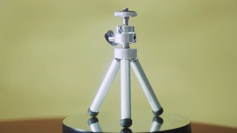 Mini-tripod,-silver-metallic-on-a-rotating-stand-360,-slow-motion,-4K