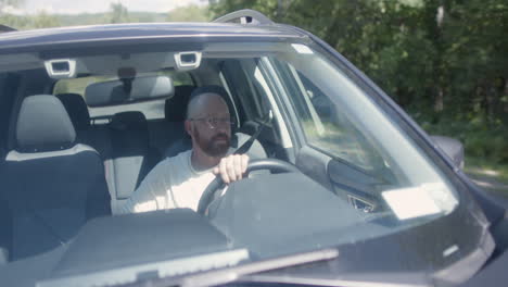 A-bald-man-peacefully-driving-a-Subaru-on-a-rural-road