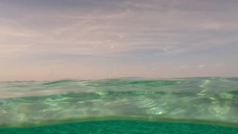 Half-underwater-of-sailing-yacht-moored-on-the-horizon,-seawater-surface-perspective