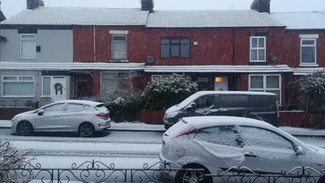 Snow-covered-vehicles-parked-outside-English-red-brick-terrace-houses-on-snowy-winter-morning