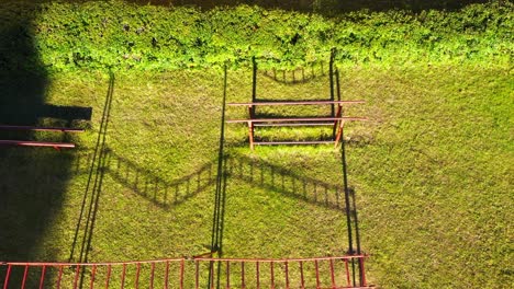 Rustic-steel-outdoor-gym-equipment-in-local-park-on-warm-sunny-day,-aerial-view