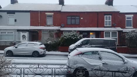 Snow-covered-vehicles-parked-outside-British-red-brick-terrace-houses-on-snowy-winter-morning
