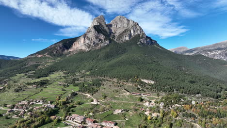Impresionante-Vista-Aérea-De-La-Montaña-Pedraforca-A-Través-Del-Paisaje-Boscoso-Del-Pueblo-De-Saldes-Hacia-El-Pico-Rocoso-De-La-Horca