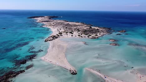 Elafonisi-beach-in-Crete-with-shallow-waters-surrounding-the-shore-with-blue-sky,-pink-sand
