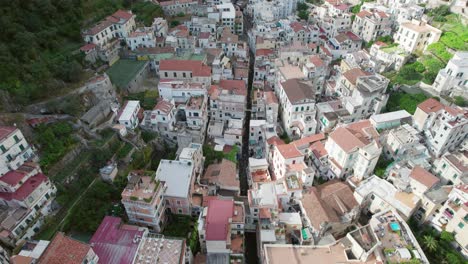 An-aerial-shot-moving-slowly-overhead-the-rustic-slate-rooftops-and-narrow-central-road-in-historic-Amalfi-town,-one-of-the-most-popular-tourist-destinations-on-the-famous-Amalfi-Coast-in-Italy