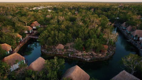Aerial-view-of-luxury-beach-wooden-houses-in-a-tropical-resort-surrounded-by-trees,-in-Tulum,-Mexico
