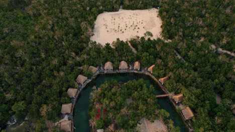 Aerial-panoramic-view-of-luxury-beach-wooden-houses-in-a-tropical-resort-surrounded-by-trees,-in-Tulum,-Mexico
