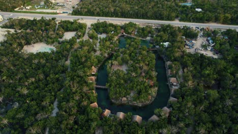 Aerial-landscape-view-of-luxury-beach-wooden-houses-in-a-tropical-resort-surrounded-by-trees,-in-Tulum,-Mexico