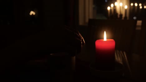 Kerze-In-Gemütlicher-Atmosphäre-Und-Hand,-Die-Nachts-Eine-Tasse-Hält