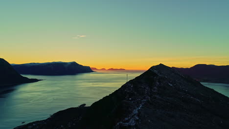 Impresionante-Vista-De-Hermosas-Montañas-Y-Puesta-De-Sol-Naranja-Que-Revela-Un-Lago-En-Noruega