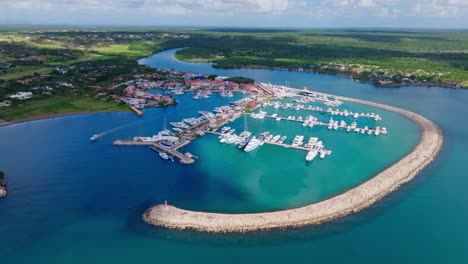 Cinematic-of-luxury-marina-with-river-in-background-and-green-island-of-Dominican-Republic