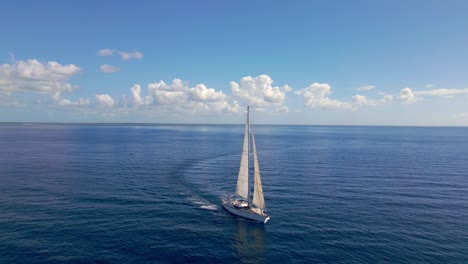 Picturesque-scene-of-Oyster-luxury-sailing-yacht-cruising-on-flat-sea-with-perfect-blue-sky-and-puffy-clouds-on-horizon