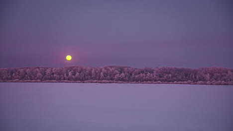 Timelapse-shot-of-snow-covered-winter-landscape-with-moon-rising-during-evening-time