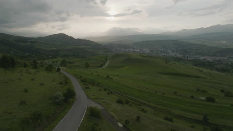 Rural-Road-Surrounded-With-Vast-Green-Fields-In-Samtskhe-Javakheti,-Near-Akhaltsikhe-In-Georgia---aerial-pullback