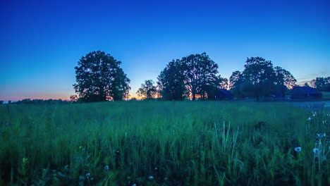 Green-meadow-and-small-cottage-homes-in-rural-landscape,-early-morning-fusion-time-lapse