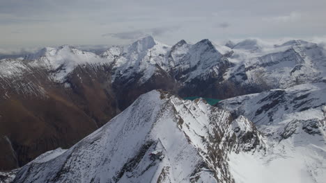 Majestätische-Schneebedeckte-Berge-österreichs-Und-Grüner-See-Im-Tal-Bei-Sonnigem-Tag---Luftvorwärtsflug