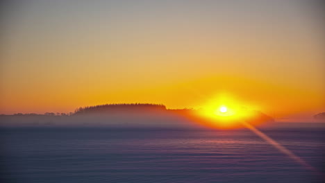 Shot-of-beautiful-sunrise-on-a-cold-winter-morning-over-the-snow-covered-landscape-in-timelapse