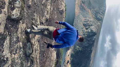 Man-holding-camera-walks-to-scenic-lake-view-Vertical-Video