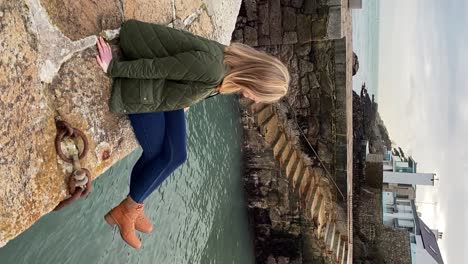 Young-woman-sitting-on-Irish-Harbour-swinging-her-legs