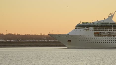Kreuzfahrtschiff-Verlässt-Den-Hafen-Bei-Sonnenuntergang,-Passagiere-Bewegen-Sich-Auf-Deck-Weitwinkelaufnahme