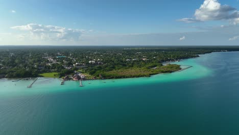 Aerial-view-overlooking-the-Bacalar-village,-in-sunny-Mexico---rising,-drone-shot