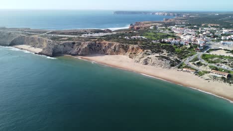 Die-Berühmte-Portugiesische-Stadt-Sagres,-Gefilmt-Von-Drohne-Aus-Der-Mareta-Bucht,-Perfektes-Wetter-Und-Wellen