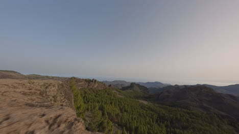 FPV-drone-pilot-speeding-across-Roque-Nublo-sunset-mountain-valley-landscape,-Gran-Canaria