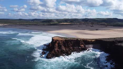 Drone-Vuela-Sobre-El-Acantilado-En-La-Impresionante-Playa-De-Bordeira-En-El-Sur-De-Portugal,-Clima-Perfecto-Con-Algunas-Nubes-Pequeñas-Y-Agradables