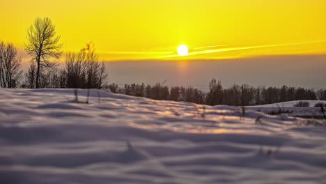 Ground-level-time-lapse-of-setting-sun-into-yellow-sky-over-snowy-landscape
