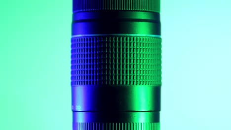 Teleobjetivo-Profesional-Bajo-Luces-Verdes-Y-Azules,-Toma-De-Estudio-Con-Movimiento-Giratorio