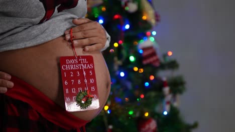 Eine-Schwangere-Frau,-Die-Ihren-Bauch-Mit-Weihnachtsschmuck-Zeigt