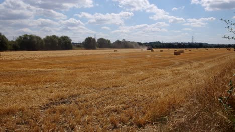 Extra-wide-shot-of-a-hey-field-with-tractor-making-hay-bales