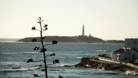 Distance-out-of-focus-Trafalgar-light-house-standing-on-the-big-island-as-the-waves-move-in-slow-motion
