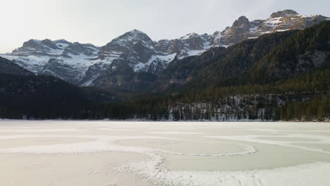 Cinematic-Flight-Above-Frozen-Lake-Tovel-Surrounded-By-Dense-Forest-On-A-Cold-Winter-Morning-In-Trentino,-Italy