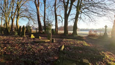 FPV-flying-around-headstones-in-snowy-sunrise-churchyard-cemetery-during-winter-golden-hour