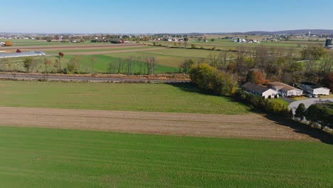 A-Slow-Traveling-Aerial-View-of-Farmlands-With-Two-Rail-Road-Tracks-Traveling-Thru-it-on-a-Sunny-Fall-Day