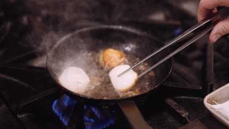 Chef-cooking-scallops-on-smoking-pan,-tight