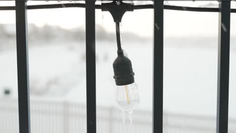 Icicles-forming-on-an-outdoor-lightbulb-during-a-snow-storm---isolated-close-up